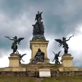 Dramatic view of the Simón Bolívar monument in Colombia beneath a cloudy sky, showcasing historical statues.