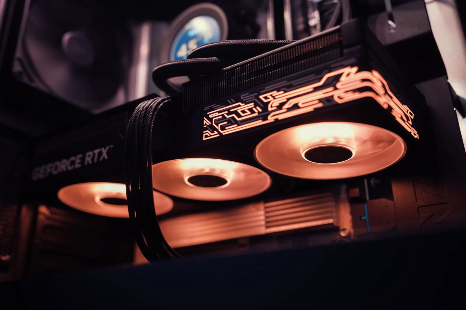 Imagen detallada de una GPU GeForce RTX con luces LED brillantes dentro de una carcasa de computadora.