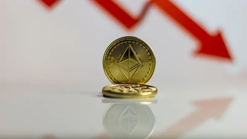 Primer plano de la criptomoneda Ethereum con una flecha roja hacia abajo, simbolizando la caída del mercado.