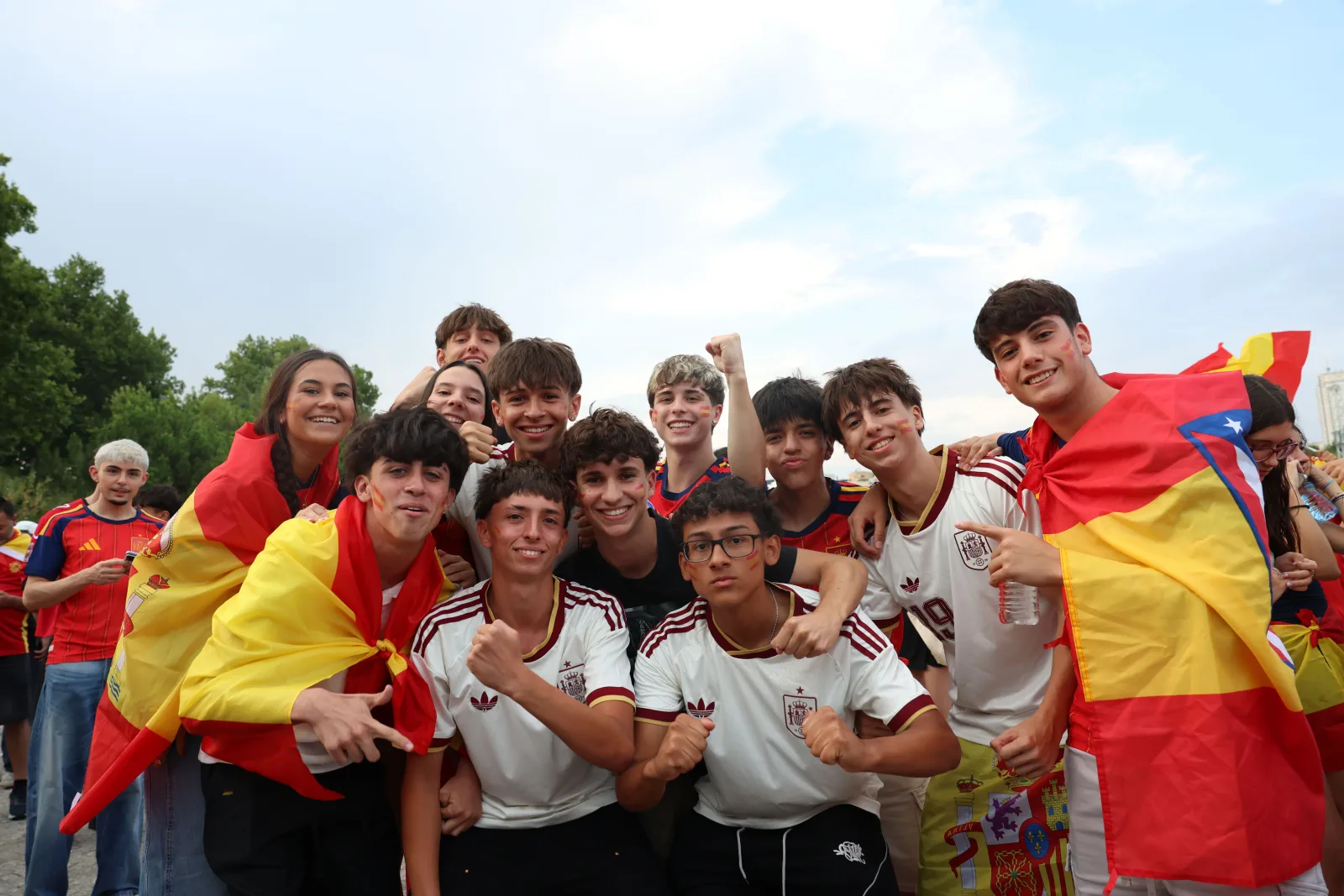 Un grupo de entusiastas aficionados del fútbol español celebrando al aire libre en Madrid.