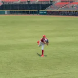 A baseball player pitching on a grass field in an empty stadium.