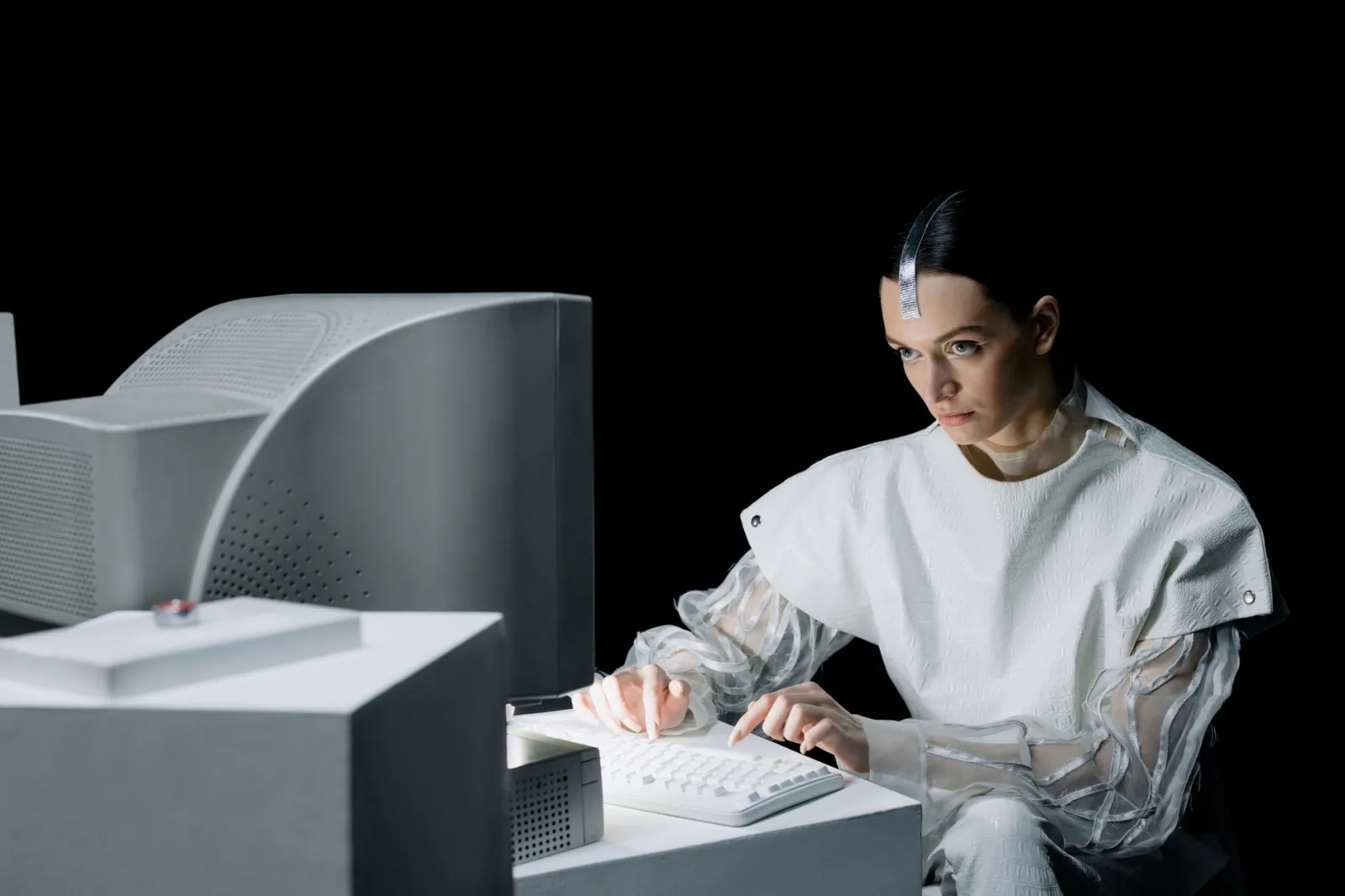 Una mujer en un entorno futurista trabajando en una computadora antigua, lo que sugiere una mezcla de pasado y futuro.