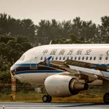 Avión de China Southern Airlines en la pista, rodeado de exuberante vegetación.