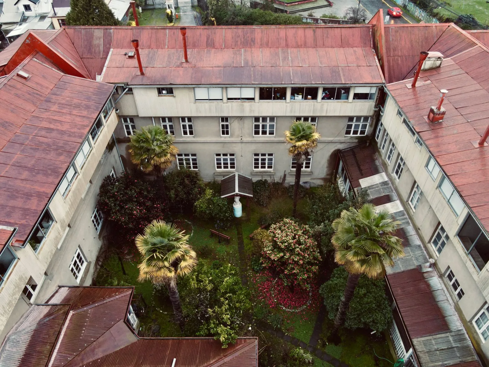 Vista aérea de un frondoso patio rodeado de edificios históricos en Valdivia, Chile.