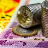 Primer plano detallado de monedas apiladas y billetes que ilustran conceptos financieros.