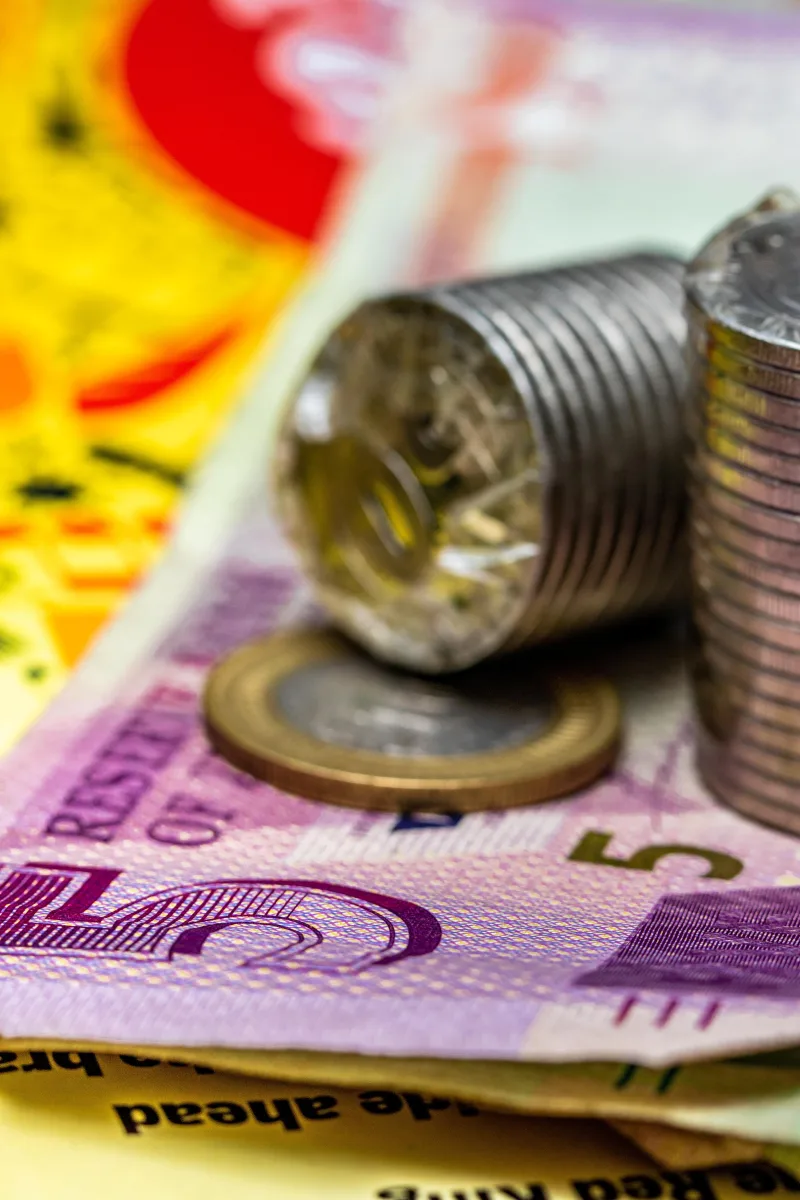 Primer plano detallado de monedas apiladas y billetes que ilustran conceptos financieros.
