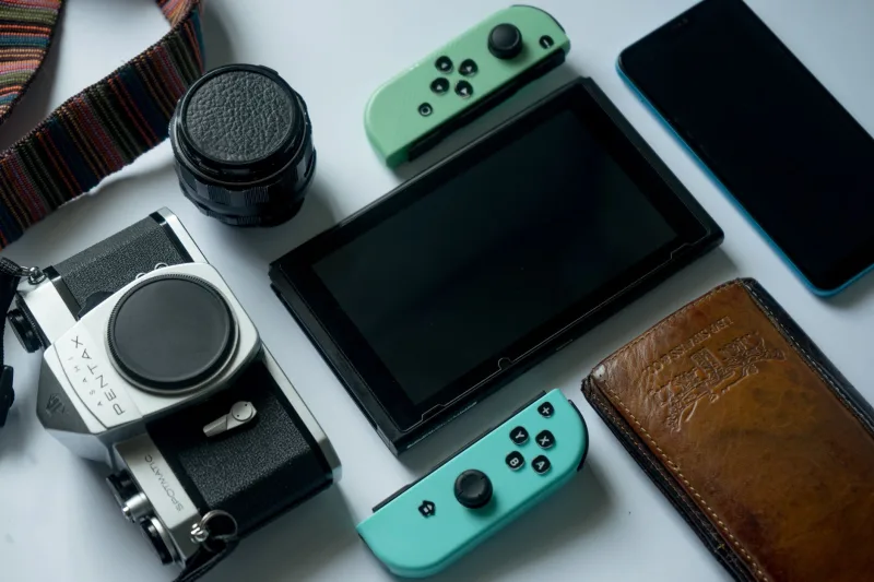 A composition of modern gadgets including a gaming console, smartphone, and a retro camera.