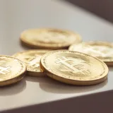 Primer plano de brillantes monedas de oro de Bitcoin sobre una superficie blanca, que simbolizan la riqueza en criptomonedas.