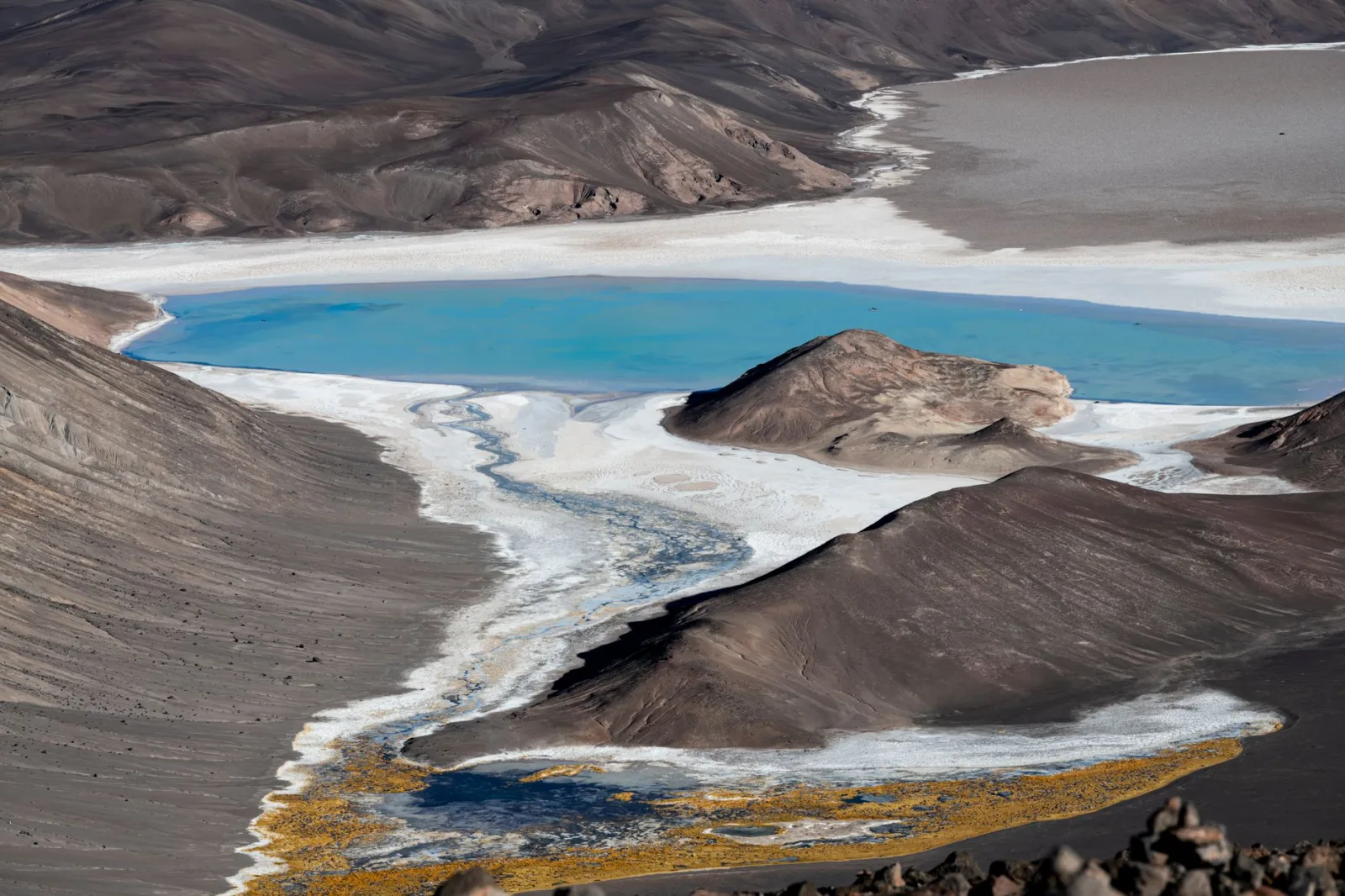 Impresionante vista aérea de un lago turquesa en medio de un paisaje desértico en Catamarca, Argentina.