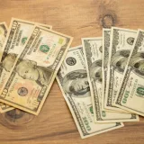 Una colección de billetes de dólar estadounidense dispuestos sobre una superficie de madera, que muestra distintas denominaciones.