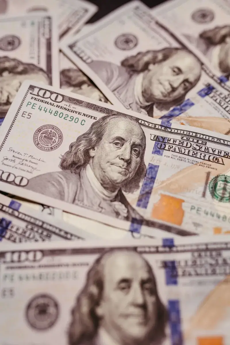 Foto de alta resolución de billetes de cien dólares estadounidenses dispuestos, mostrando a Benjamin Franklin.
