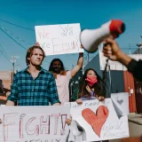 Manifestantes sosteniendo carteles que abogan por la igualdad y la paz en una zona urbana.