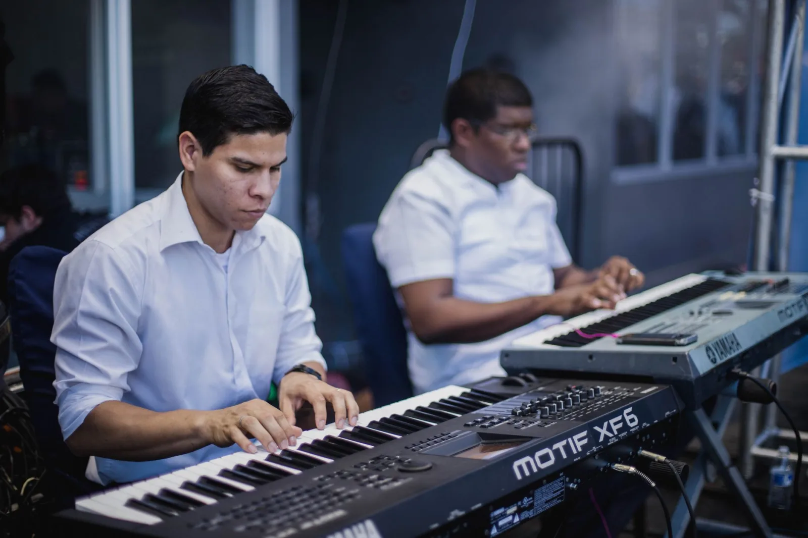 Dos músicos concentrados tocando teclados en un estudio de música.
