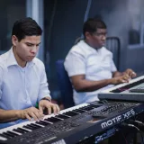 Dos músicos concentrados tocando teclados en un estudio de música.