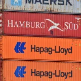 Close-up of stacked shipping containers featuring Maersk, Hamburg Süd, and Hapag-Lloyd logos.