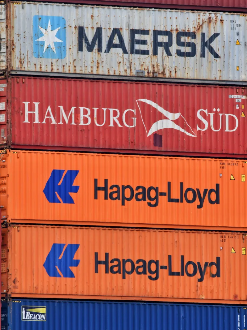 Close-up of stacked shipping containers featuring Maersk, Hamburg Süd, and Hapag-Lloyd logos.
