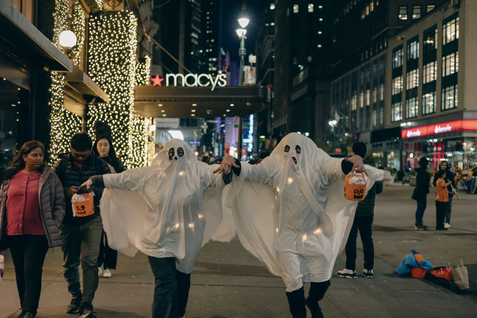 Adultos disfrazados de fantasmas caminan de noche por la ciudad de Nueva York para celebrar Halloween.