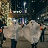 Adultos disfrazados de fantasmas caminan de noche por la ciudad de Nueva York para celebrar Halloween.