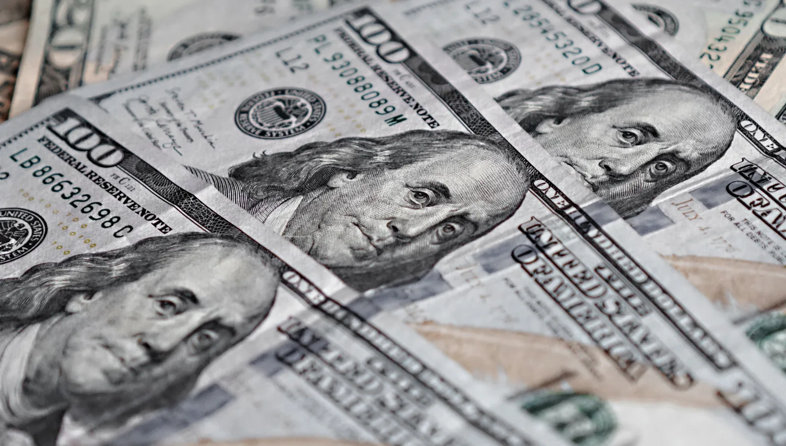 Vista de cerca de varios billetes de cien dólares estadounidenses con el retrato de Benjamin Franklin.