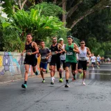Athletes running in a vibrant road race in Risaralda, Colombia, surrounded by lush greenery.