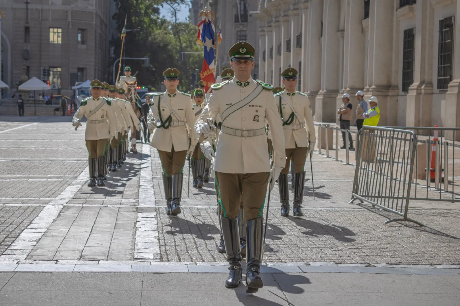 Un desfile militar con guardias uniformados marchando en Santiago de Chile en un día soleado.