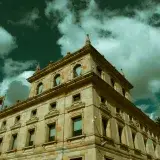 Low angle shot of a historic stone building against a cloudy sky in Bogotá, Colombia.