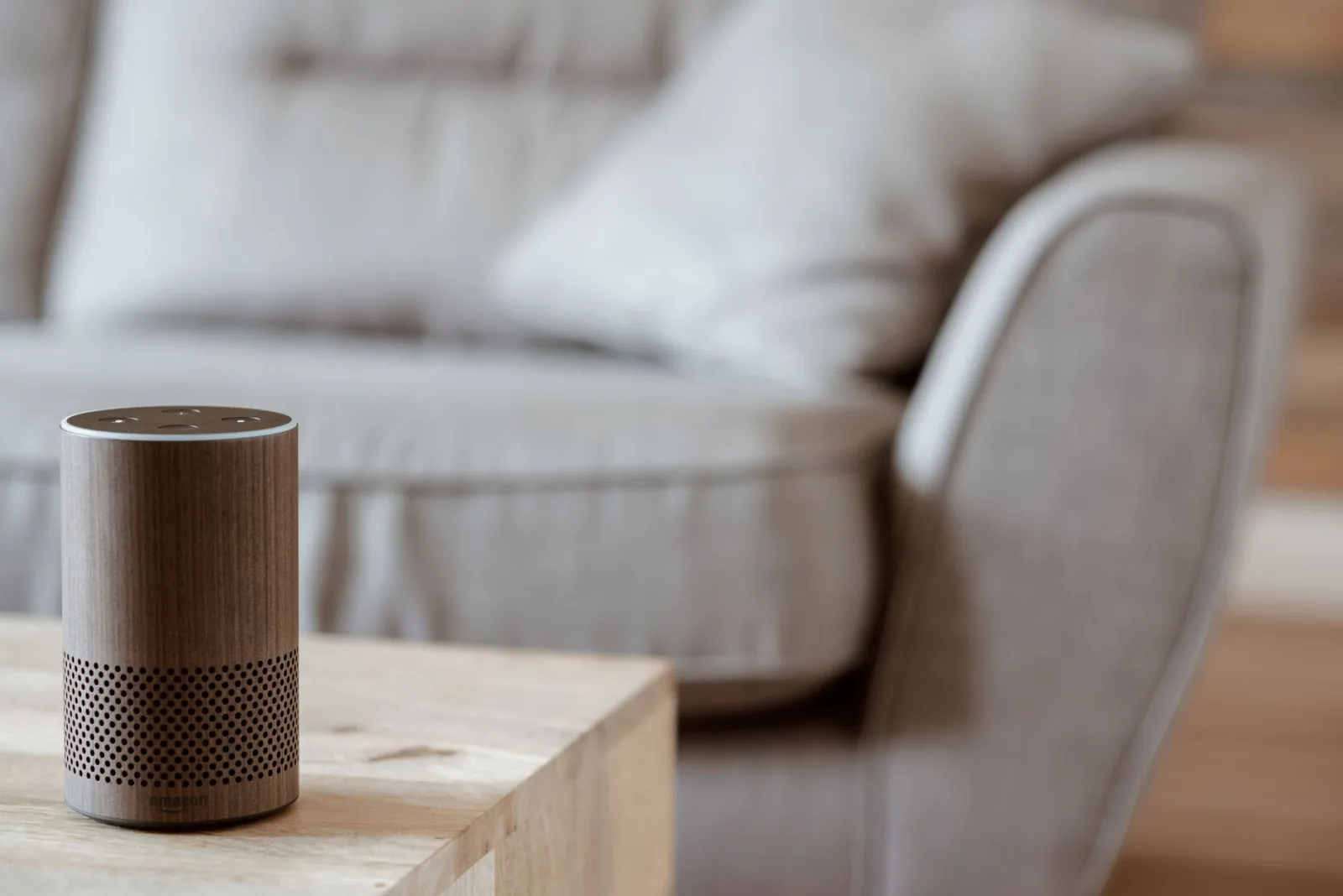 Un altavoz inteligente moderno está sobre una mesa de madera en una acogedora sala de estar de estilo minimalista.