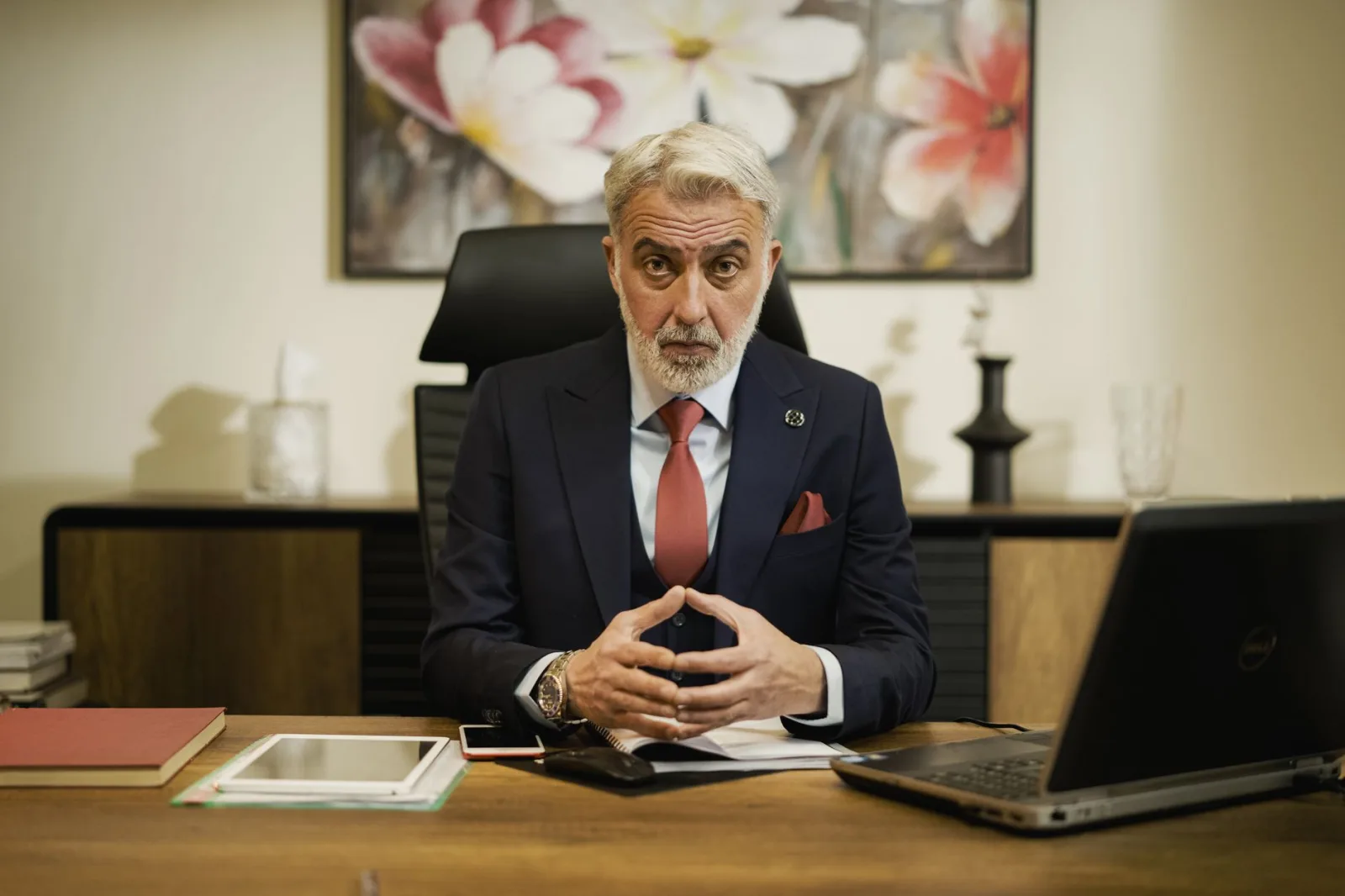 Empresario profesional de mediana edad sentado con confianza en su escritorio ejecutivo, en una oficina.