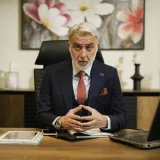 Empresario profesional de mediana edad sentado con confianza en su escritorio ejecutivo, en una oficina.