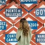 A woman observing multiple metro station signs in Madrid, Spain, showcasing urban exploration.
