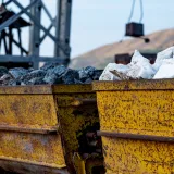 Close-up of rusty mining carts filled with various minerals in an industrial setting.