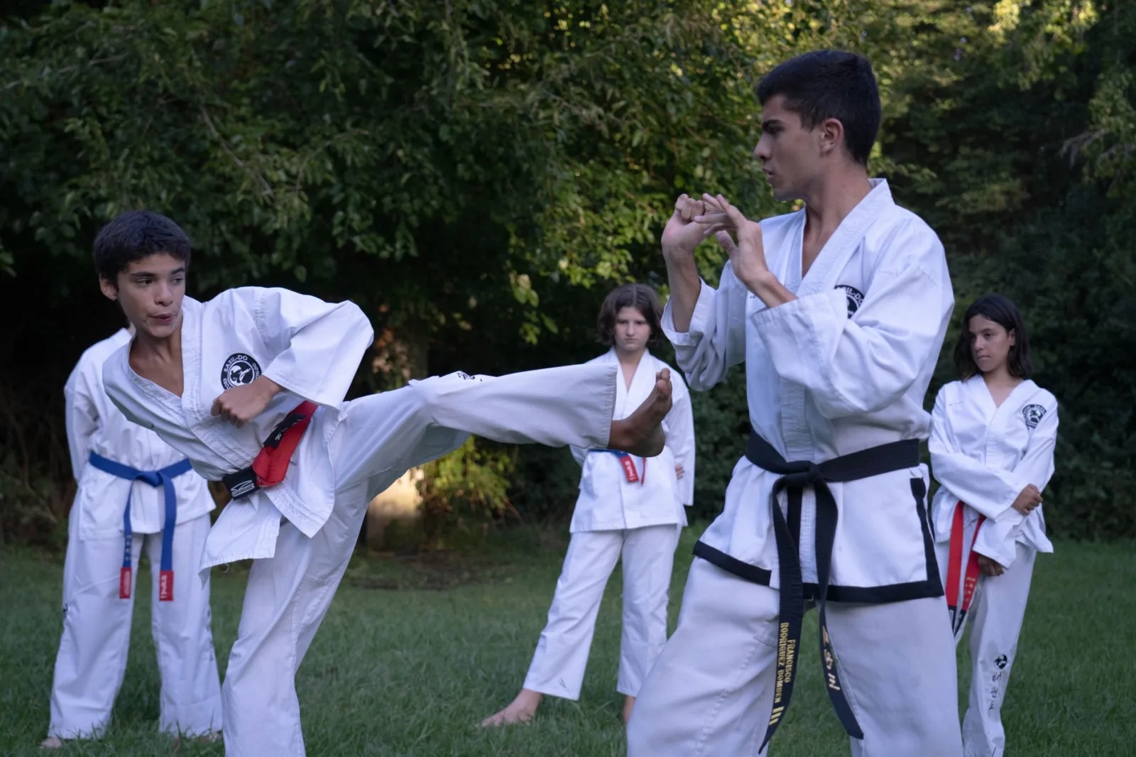 Adolescentes practicando artes marciales en un parque de Buenos Aires, demostrando concentración y disciplina.