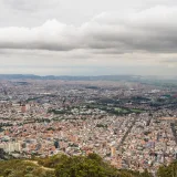 Expansive aerial view of Bogotá, Colombia, showcasing the dense urban cityscape under a cloudy sky.