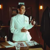 Confident woman in white suit presenting a case in an elegant courtroom setting.