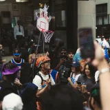 Animada escena callejera de aficionados al baloncesto que llevan camisetas y celebran junto a una canasta pequeña.