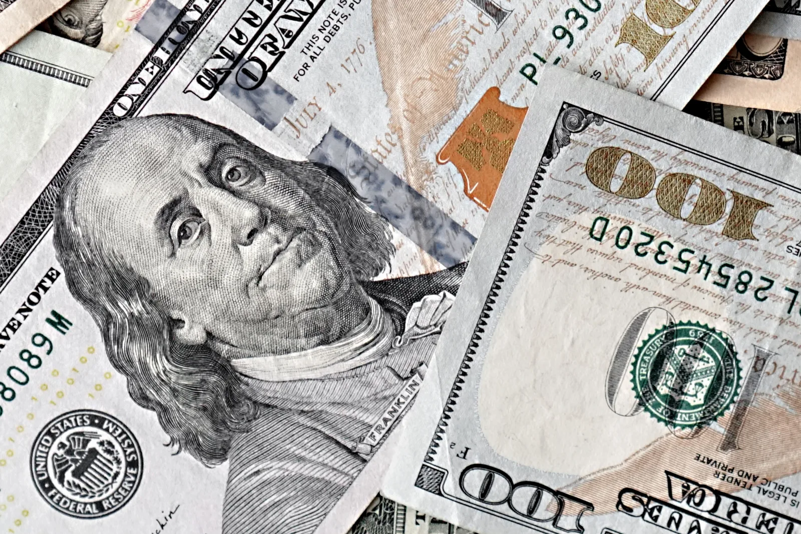Primer plano detallado de varios billetes estadounidenses de cien dólares en una disposición dispersa.